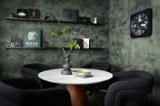 office with dark green walls with black chairs and walnut table