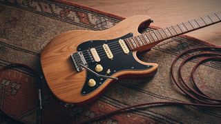A Sire Larry Carlton S7 Ash Top electric guitar lying on a rug with a guitar cable coiled nearby