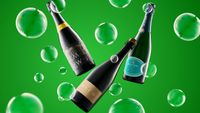 Three floating wine bottles labeled Mountfield Winery, Hugo, and Wiston, surrounded by translucent green bubbles on a green background