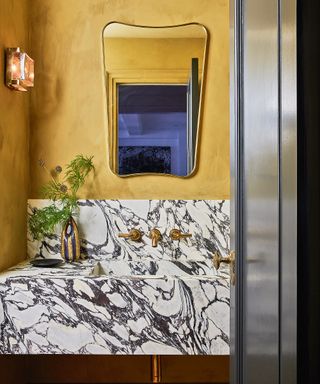 Modern powder room with gold walls and marble countertop