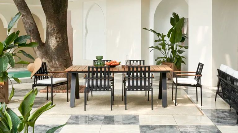 A black metal patio dining set in a courtyard with a swimming pool