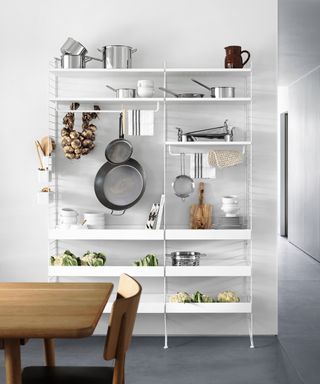 A kitchen with a minimal white metal open shelving unit.