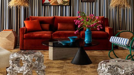 a living room with a 80 coffee table with pink tulips on in front of a red sofa