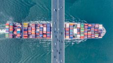 A freighter full of containers sailing under a bridge in Shenzhen City, China