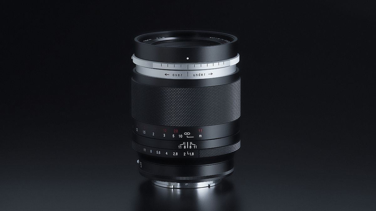 A sleek black camera lens (Voigtlander Portrait Heliar 75mm f/.8) with textured grip and aperture markings displayed, set against a dark background