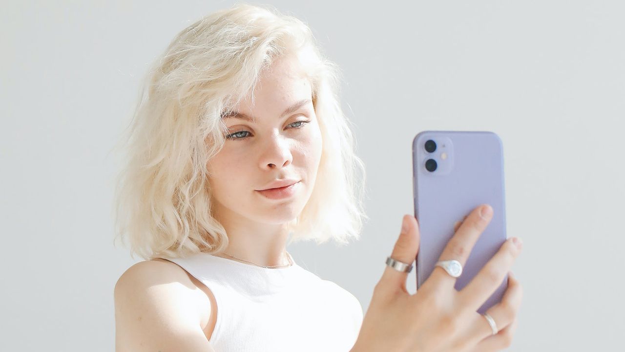 An Apple iPhone being used by a woman with white hair to take a photo of herself