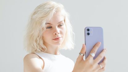 An Apple iPhone being used by a woman with white hair to take a photo of herself