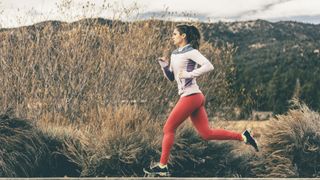 Side view of female athlete running by field