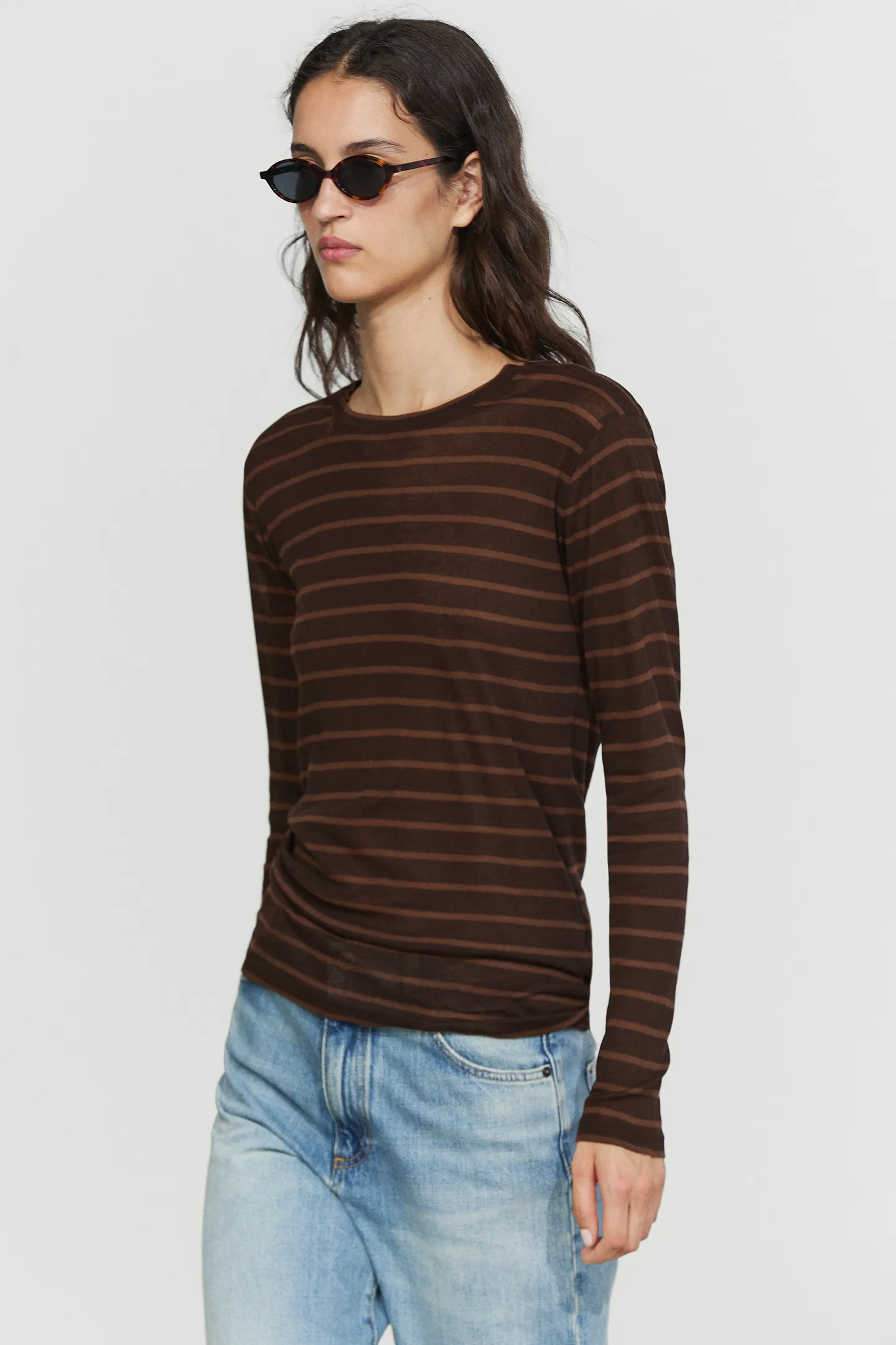 A model wearing Massimo Dutti brown striped long-sleeve t-shirt, jeans and sunglasses.