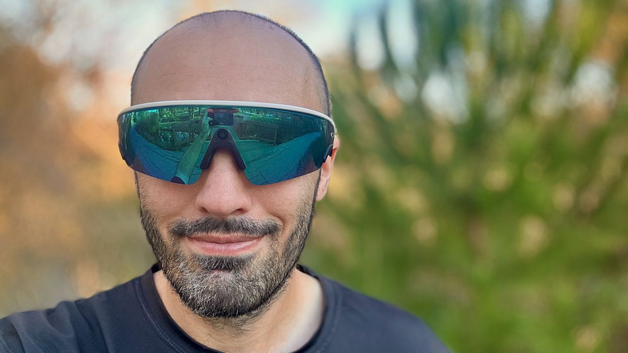 A selfie of the author wearing Oakley Meta Vanguard glasses in front of a blurred tree background.