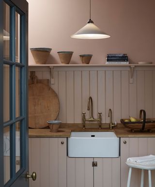 Low hanging cone pendant in utility, pink painted wooden cabinetry, blue door