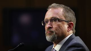 A telephoto shot of Peiter Zatko, a white man with a goatee in a suit, testifying before the Senate Judiciary Committee on data security