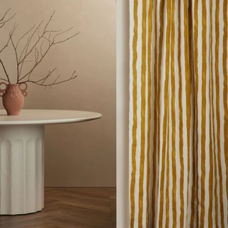 Painterly Stripe Linen Curtain Panel against a brown wall.