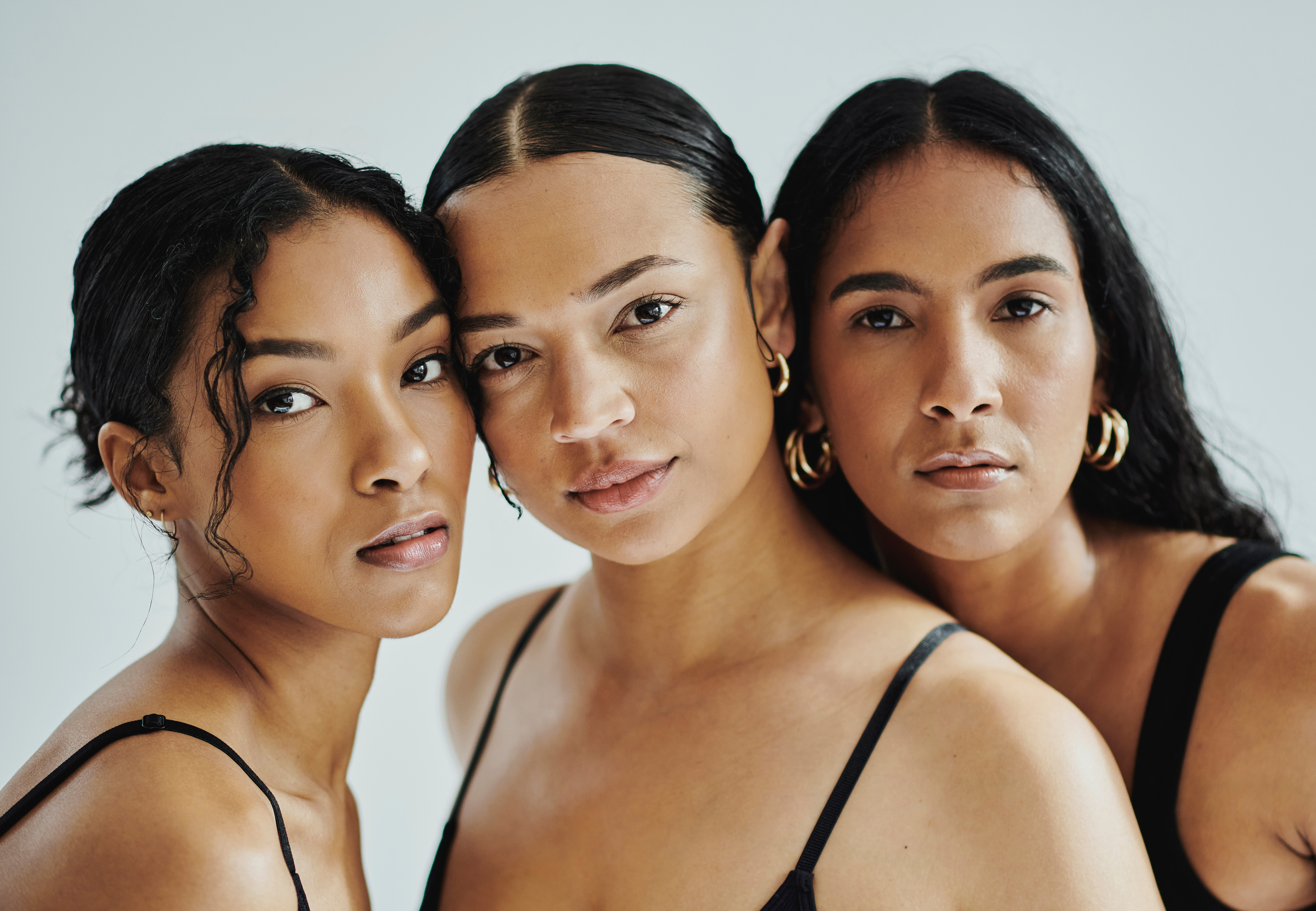 three women with diverse skin tones and glowing complexions