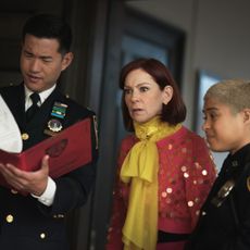 carrie preston as elsbeth looking surprised while examining paper work with two other officers