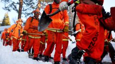 A crew of inmate firefighters walking through snow