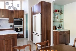 kitchen with dark wood cabinets, white marble worktops, white fridge and statement ceiling light
