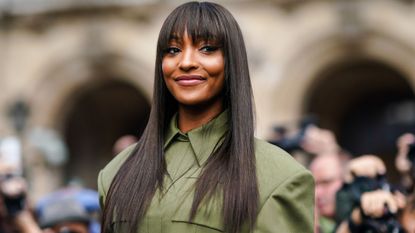 Jourdan Dunn smiling at Paris Fashion week in a green dress and long straight hair with a fringe