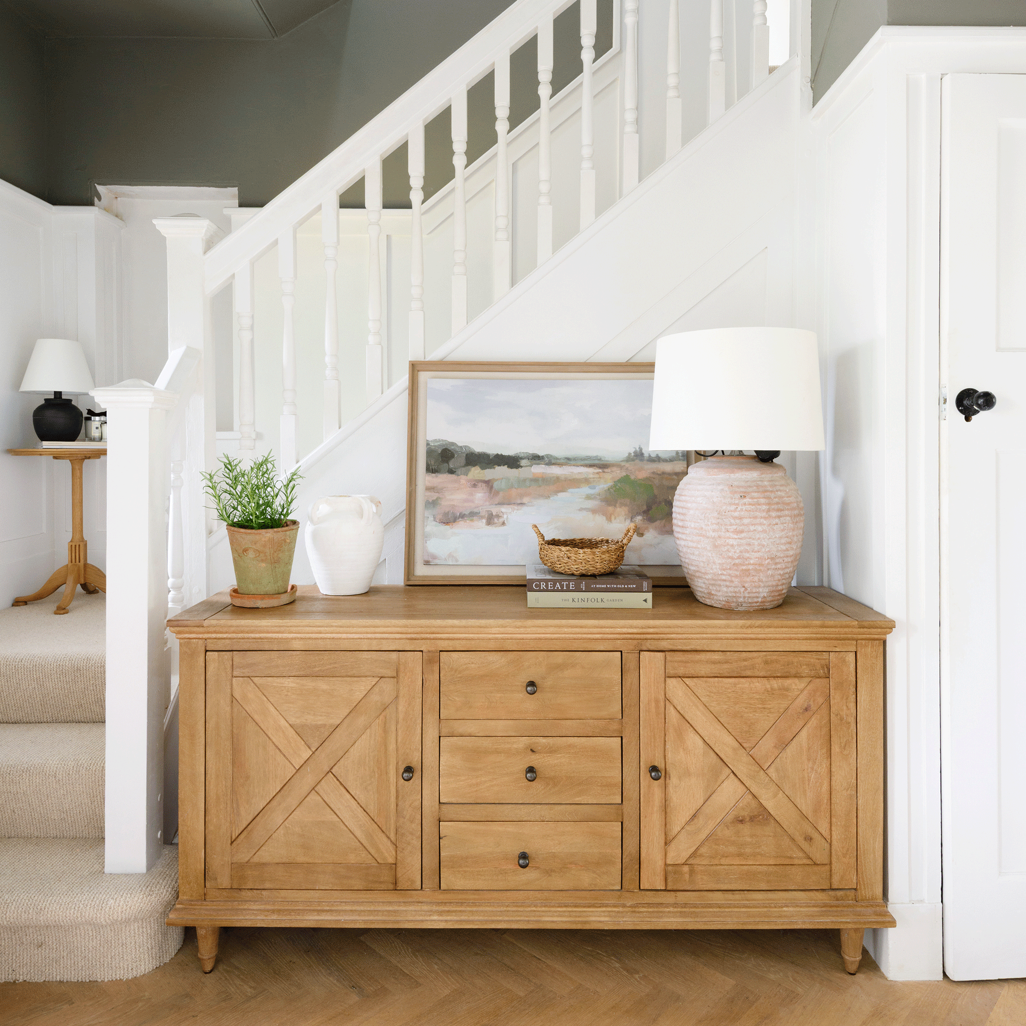 a hallway with a stairwell and sideboard