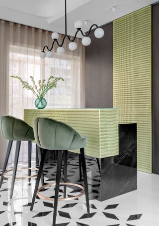 A bar area with olive green stools and a bright, pastel counter