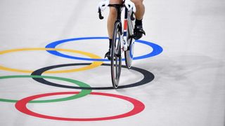 Ein Mann beim Radfahren und die olympischen Ringe