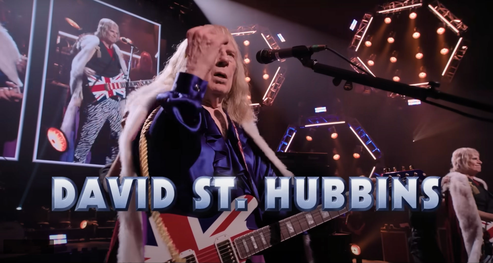 Still from Spinal Tap II depicting Union Jack-finished Ernie Ball Music Man guitars