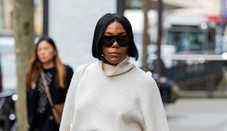 A guest wears creme white knit, denim jeans outside Dries van Noten during the Womenswear Fall/Winter 2024/2025 as part of Paris Fashion Week on February 28, 2024 in Paris, France.