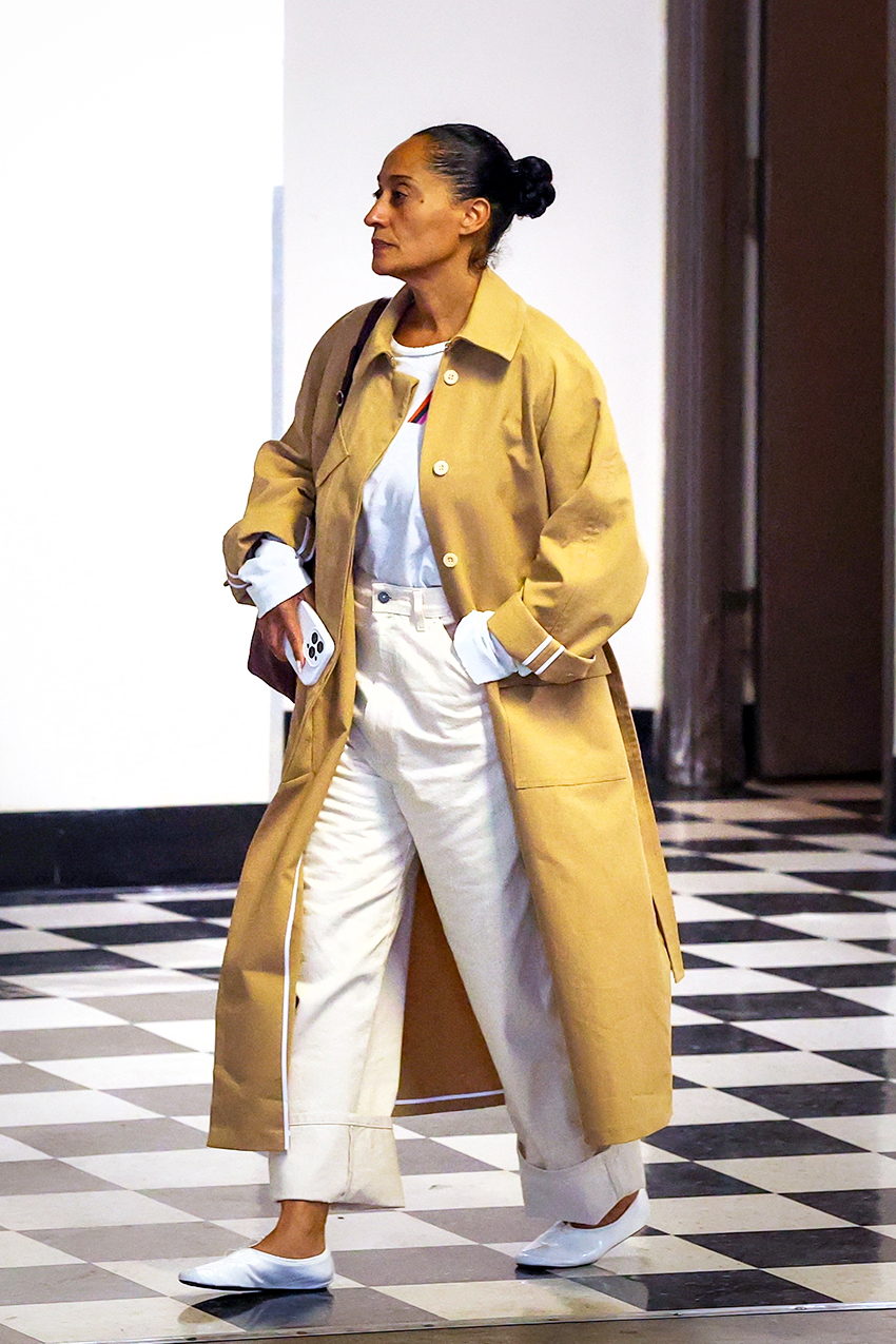 Tracee Ellis Ross wearing a tan trench coat, white tee, white jeans, and white glove flats