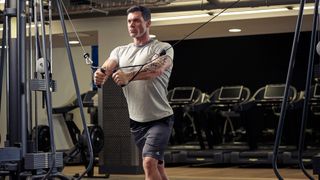 Man performs cable flye in gym