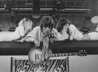 Jeff Beck (middle) leans over the stage with his Les Paul hanging around his neck