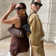 Two women posing with shoulder bags