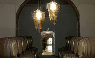 A duo of chandeliers in a room with stacked barrels.