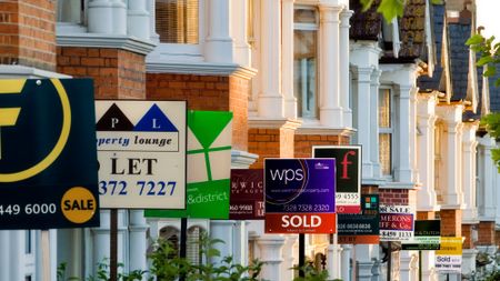 Row of houses with for sale signs in front of them