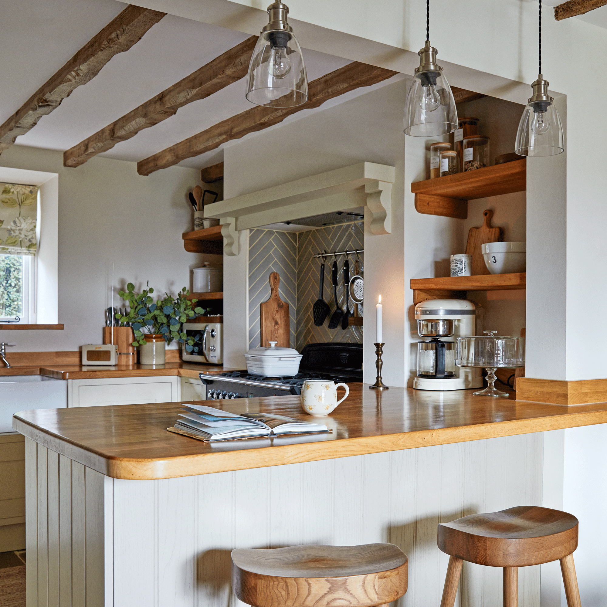 a small cream Shaker kitchen with wooden worktops with a peninsula which doubles as a breakfast bar
