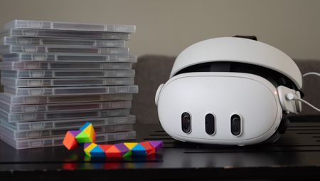 A Meta Quest 3 headset with a stack of game boxes next to it