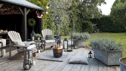 Cozy outdoor summer garden setting with fire pit bucket and seating area with adirondack chairs