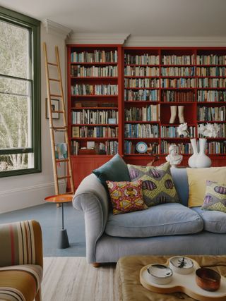 A living room with a grey sofa and a large bookshelf in the background painted an earthy red