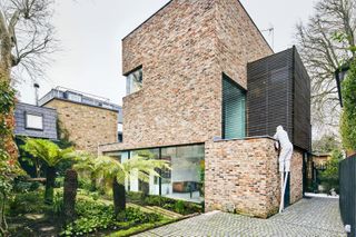 A brick self build with multiple layers and a small patch of garden to the front