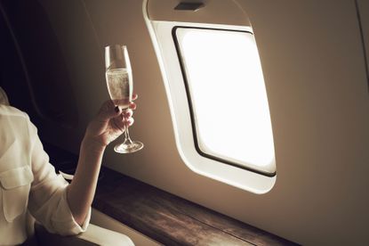 Woman relaxing with a glass of champagne aboard a private jet