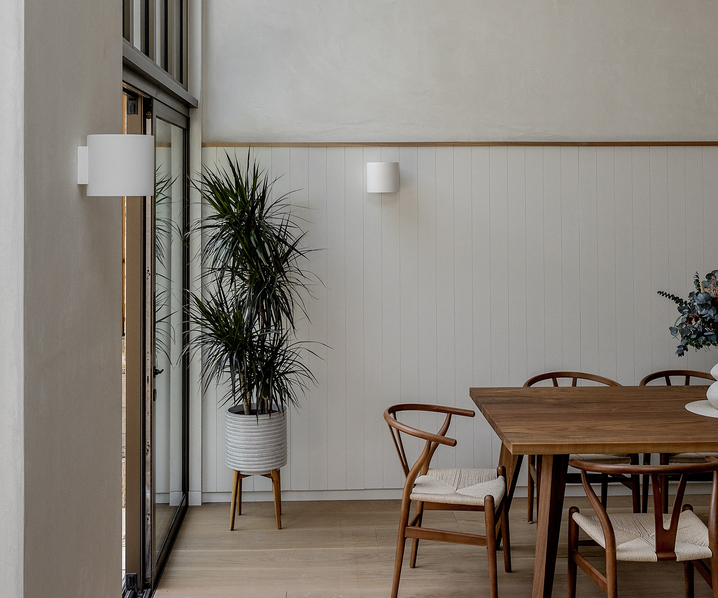 A wooden dining table in midcentury modern style in a dining room with neutral walls and pale flooring