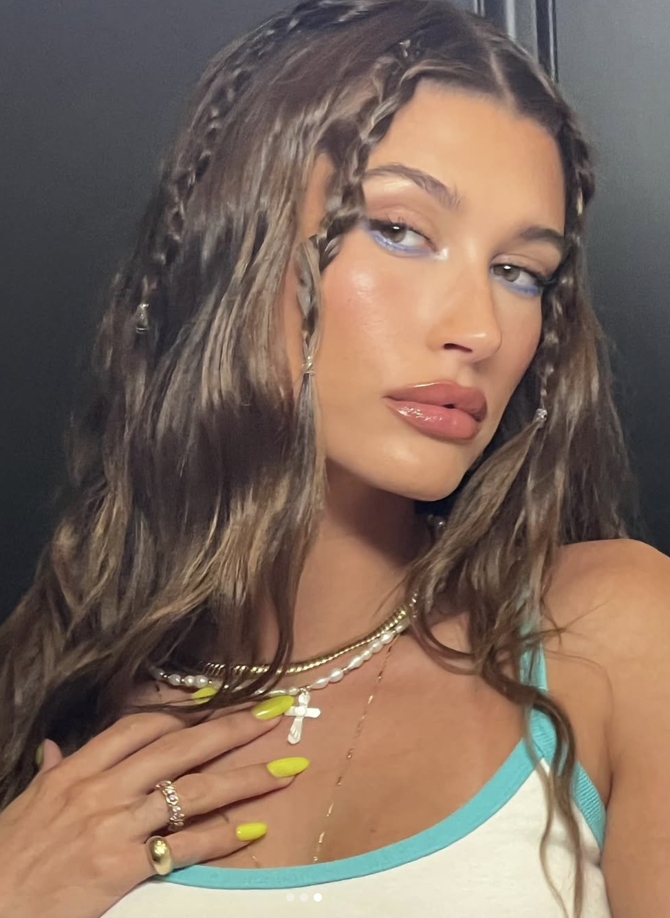 hailey bieber with blue eyeliner, lime green nails, and braided hair