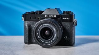 The Fujifilm X-T30 III on a stone surface with a blue background