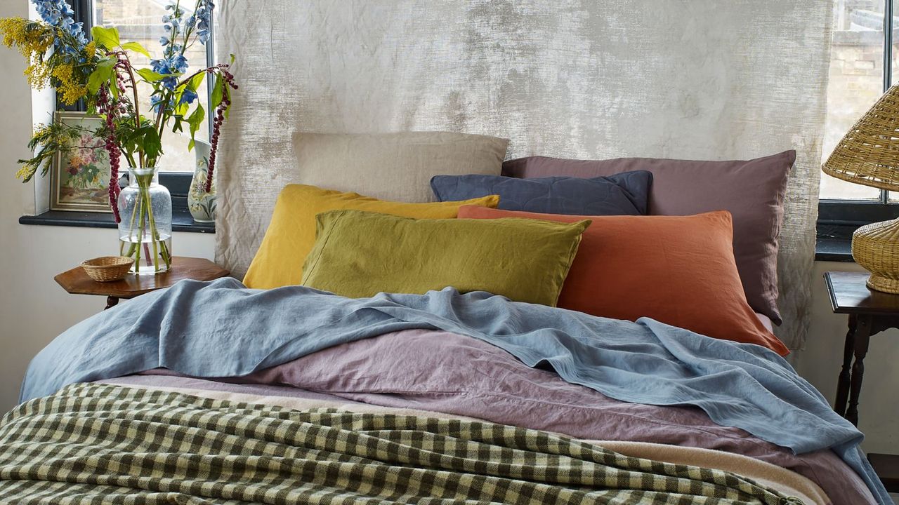 Mix-and-match bedding from Piglet in Bed on a bed against a gray wall.