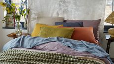 Mix-and-match bedding from Piglet in Bed on a bed against a gray wall.