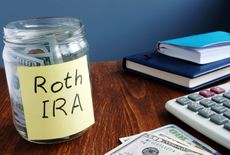 A jar with money in it with a sticky note that says Roth IRA.