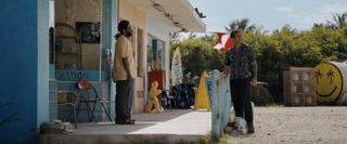 Still from Road House movie featuring two men at a shop in the sun