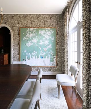 dining room with brown patterned wallpaper, large wooden dining table and light green artwork