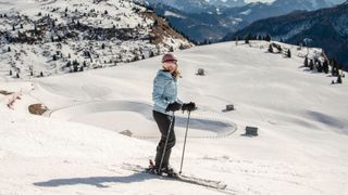 Woman standing against snowy mountains backdrop skiing