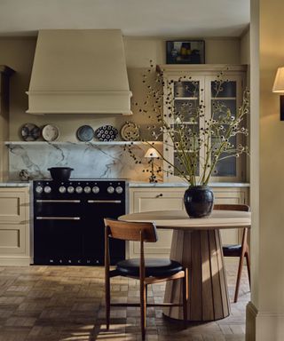 Neptune Henley kitchen painted in Lead Light paint with a black range cooker and a circular pedestal wood table styled with rustic fall branches