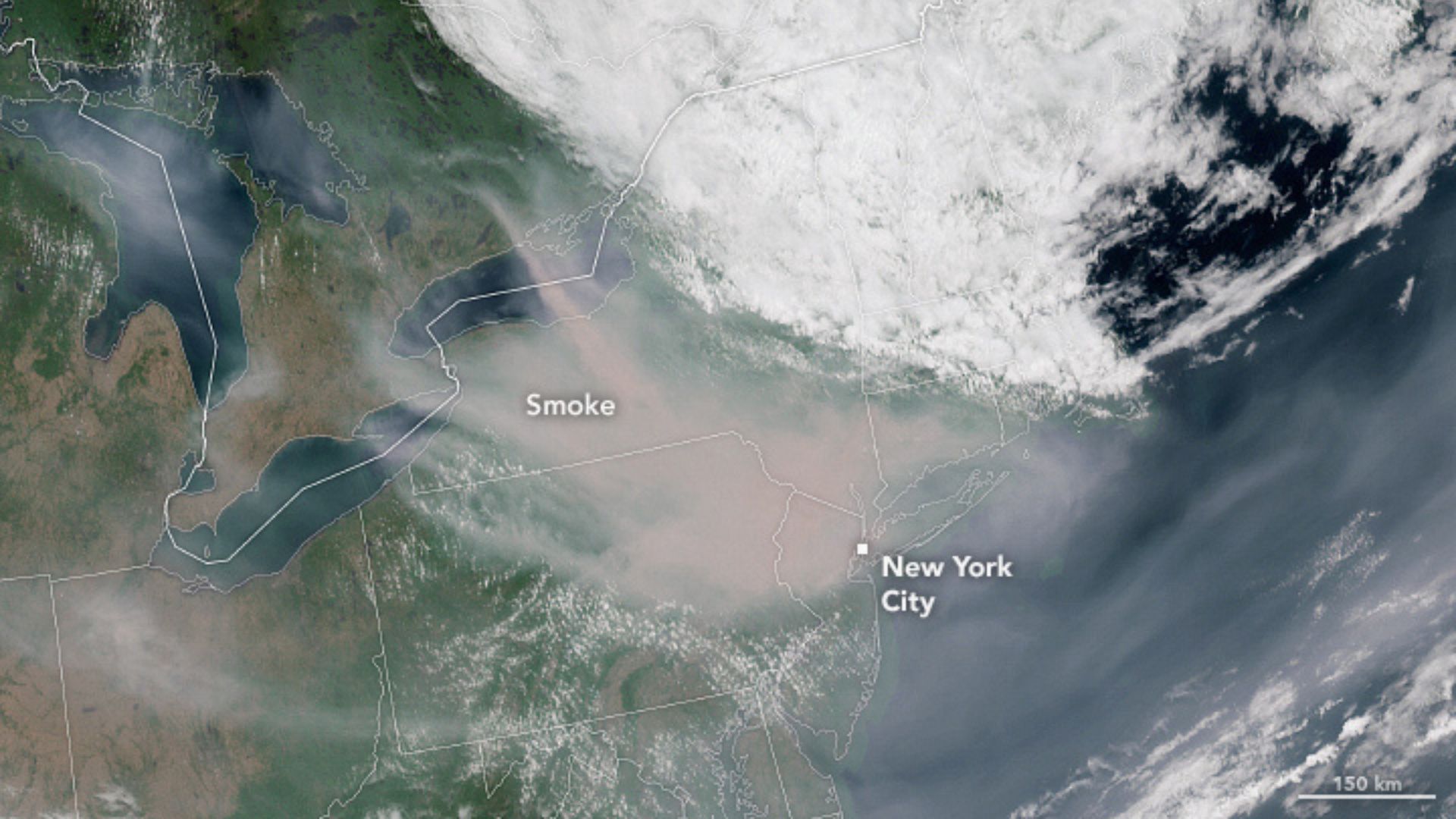 satellite photo shows the northeastern US and eastern Canada. A weather system can be seen over Maine and Nova Scotia, and a massive cloud of wildfire smoke can be seen southeast of that, floating from canada to new york city, which is labeled